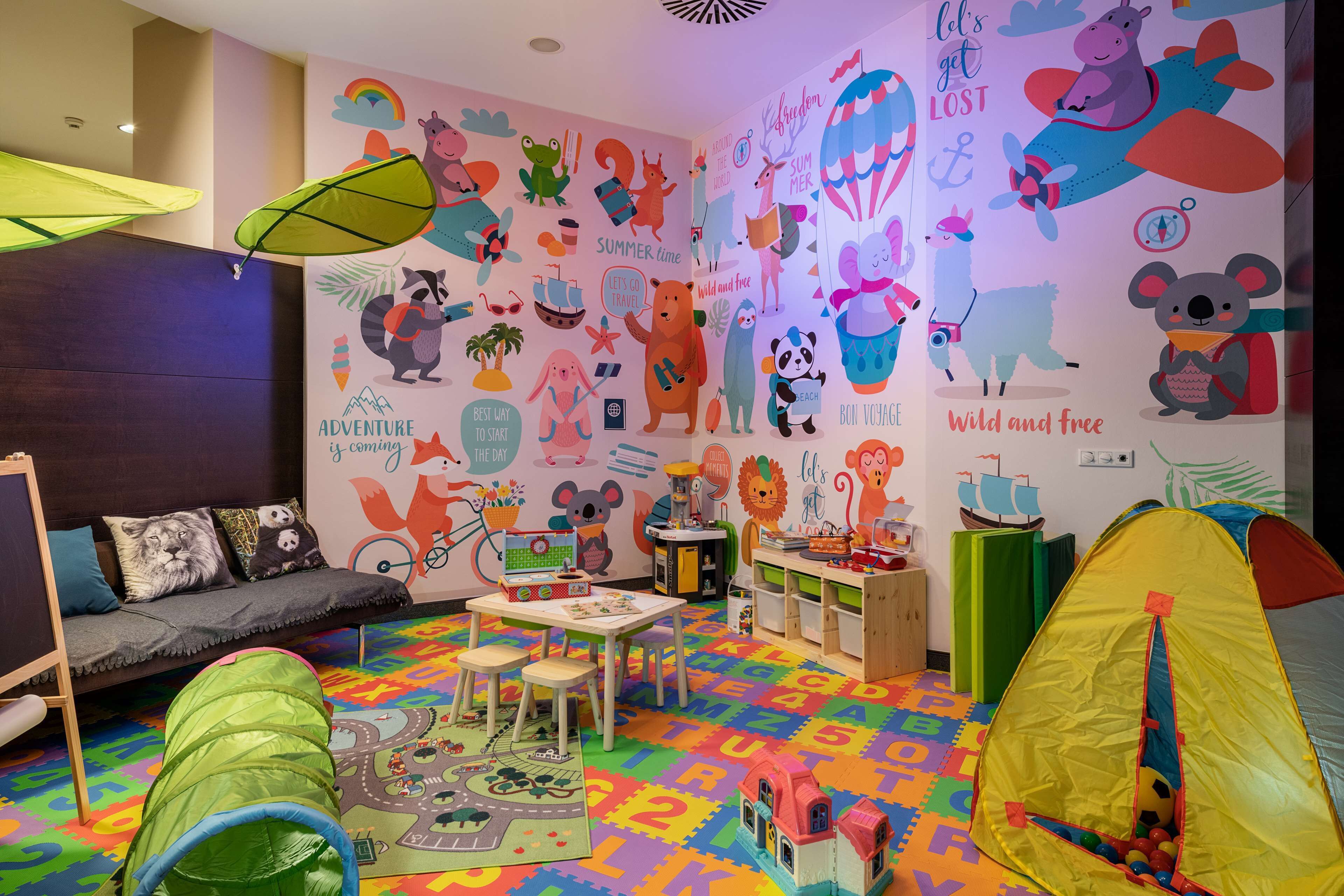 Una sala de juegos infantil con paredes coloridas, una tienda de juegos y un sofá.