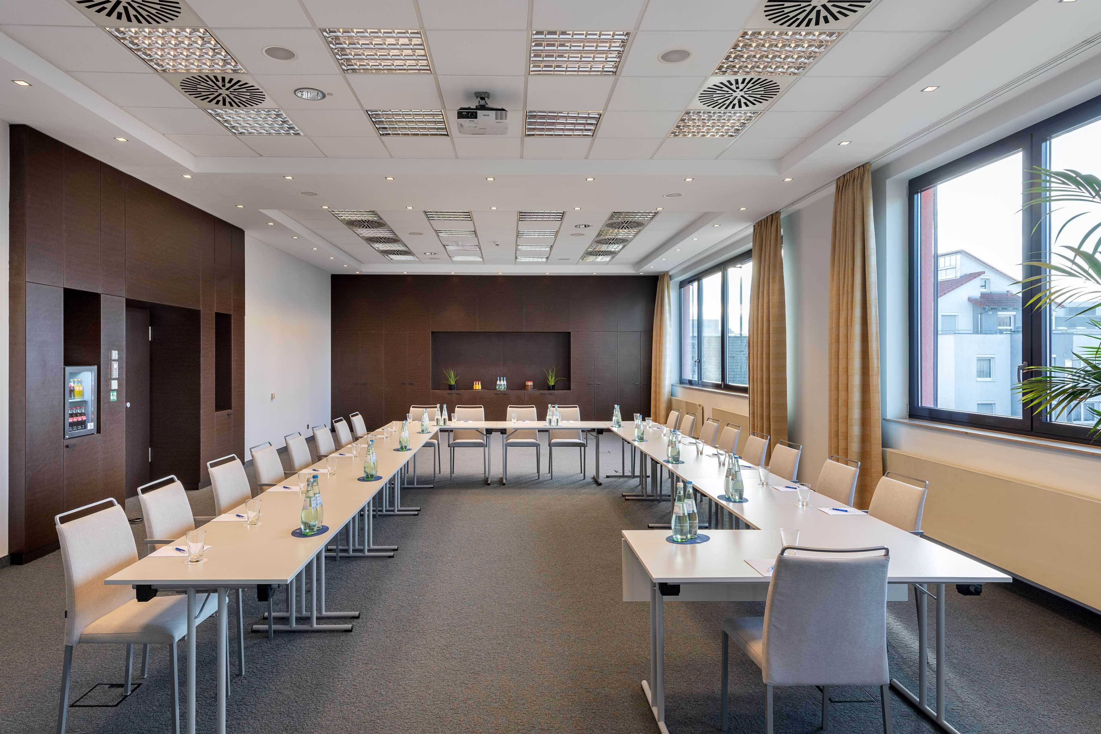 Ein Konferenzraum mit einem langen Tisch, Stühlen und einer Projektionsleinwand.