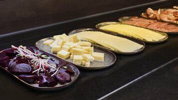 Un bufé con diversas opciones de comida, incluyendo queso, carnes y verduras.