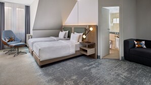 A modern hotel room with two beds, a seating area, and a view of the bathroom. - Courtyard by Marriott Schwerin (Schwerin)