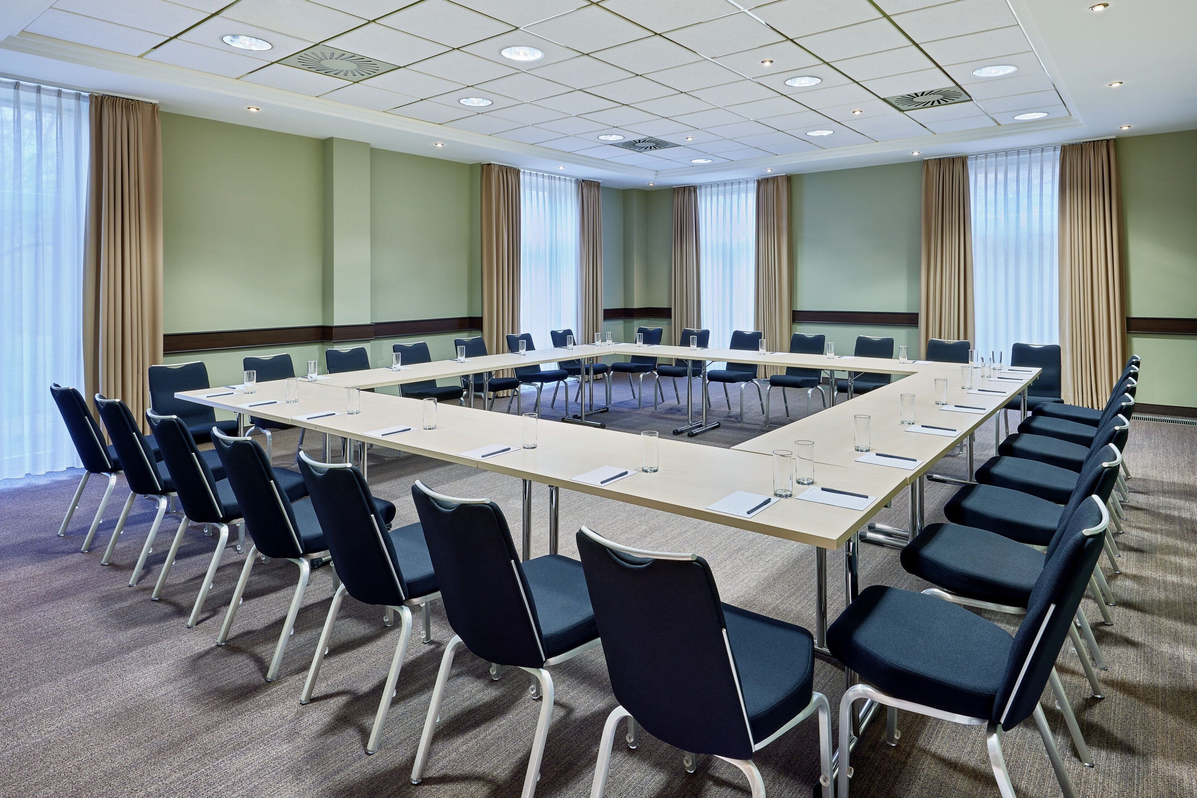 Uma sala de conferências com uma mesa comprida, cadeiras e piso coberto por carpete.