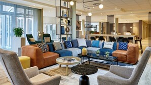 A modern living room with a sectional sofa, armchairs, a coffee table, and a bookshelf. - Courtyard by Marriott Schwerin (Schwerin)