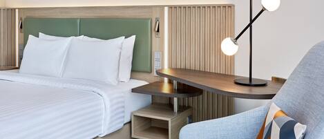 A hotel room with a bed, a nightstand, a lamp, and a chair.