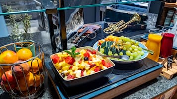 A breakfast buffet with fruits, a glass of orange juice, and a trumpet.