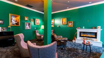 A green-themed living room with a fireplace, framed pictures on the wall, and a variety of seating options.