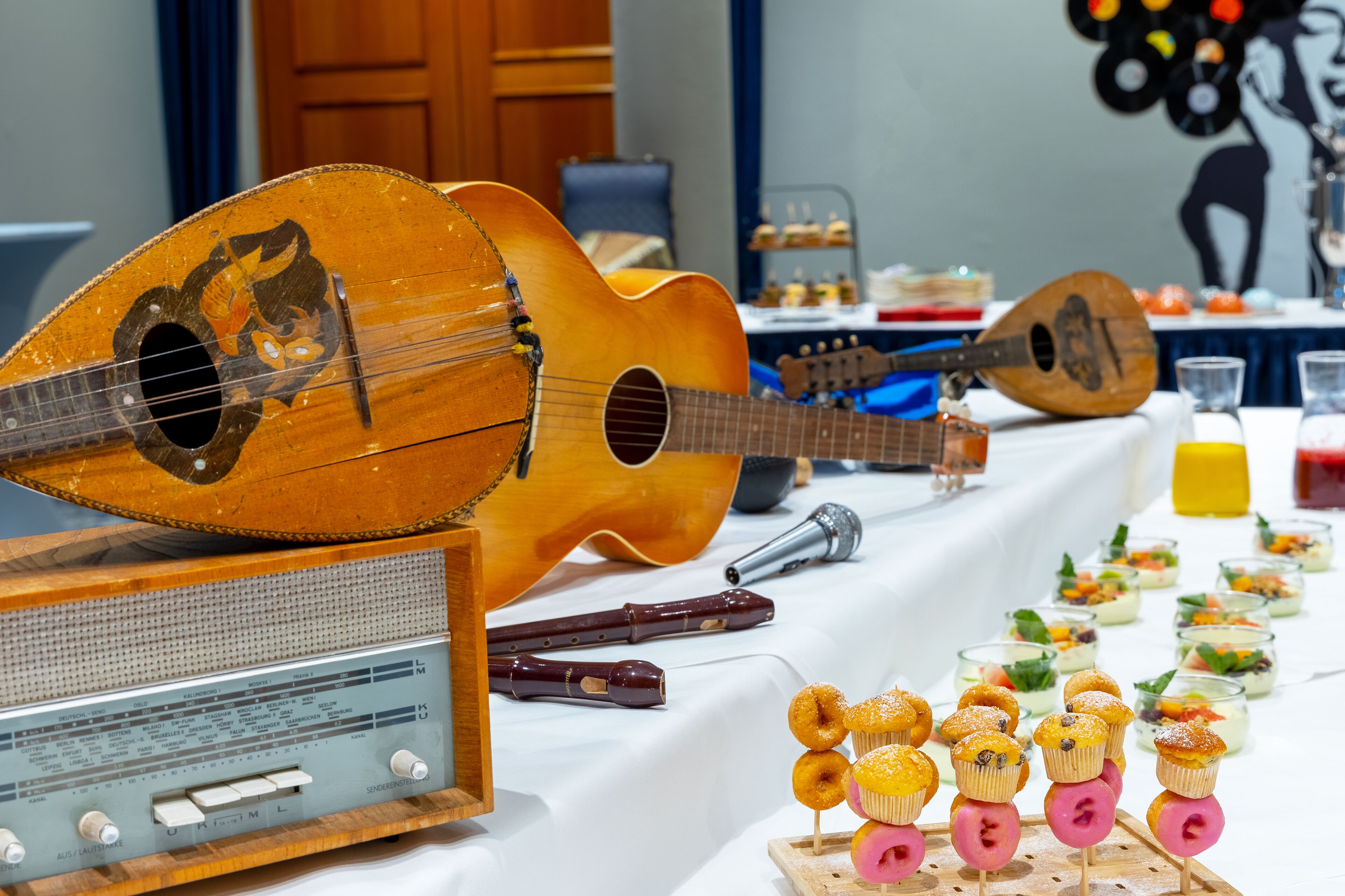 A table with a guitar, a radio, and food items.