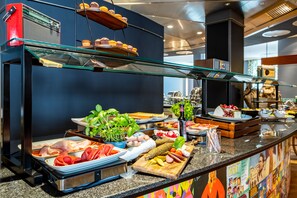 A buffet with various food items including meats, cheeses, and fruits. - mightyTwice Hotel Dresden (Dresden)