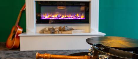 Una habitación con chimenea, una guitarra y un banjo sobre una mesa.
