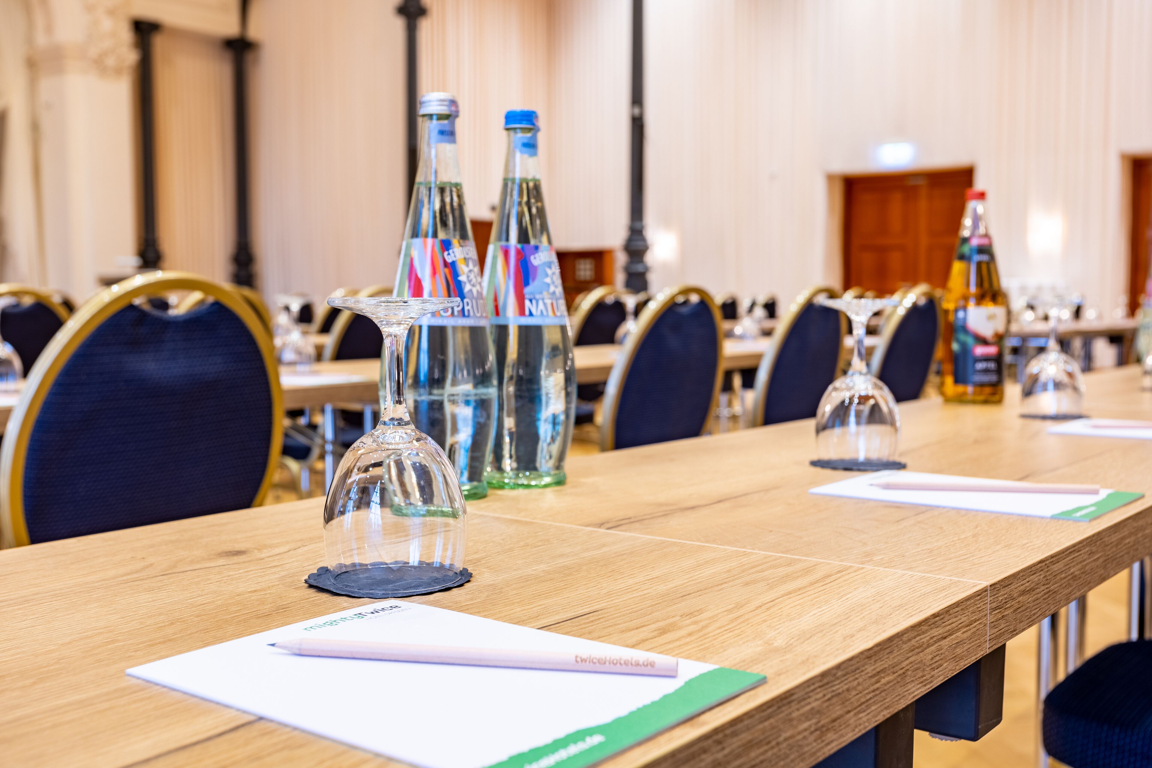 A conference room with a long table, clear glass water bottles, and a glass dome centerpiece.