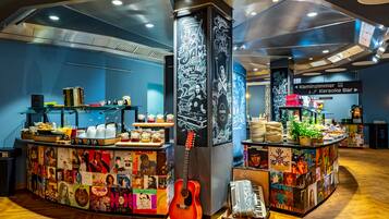A bar area with a guitar, food and drink stations, and a wall with various posters.