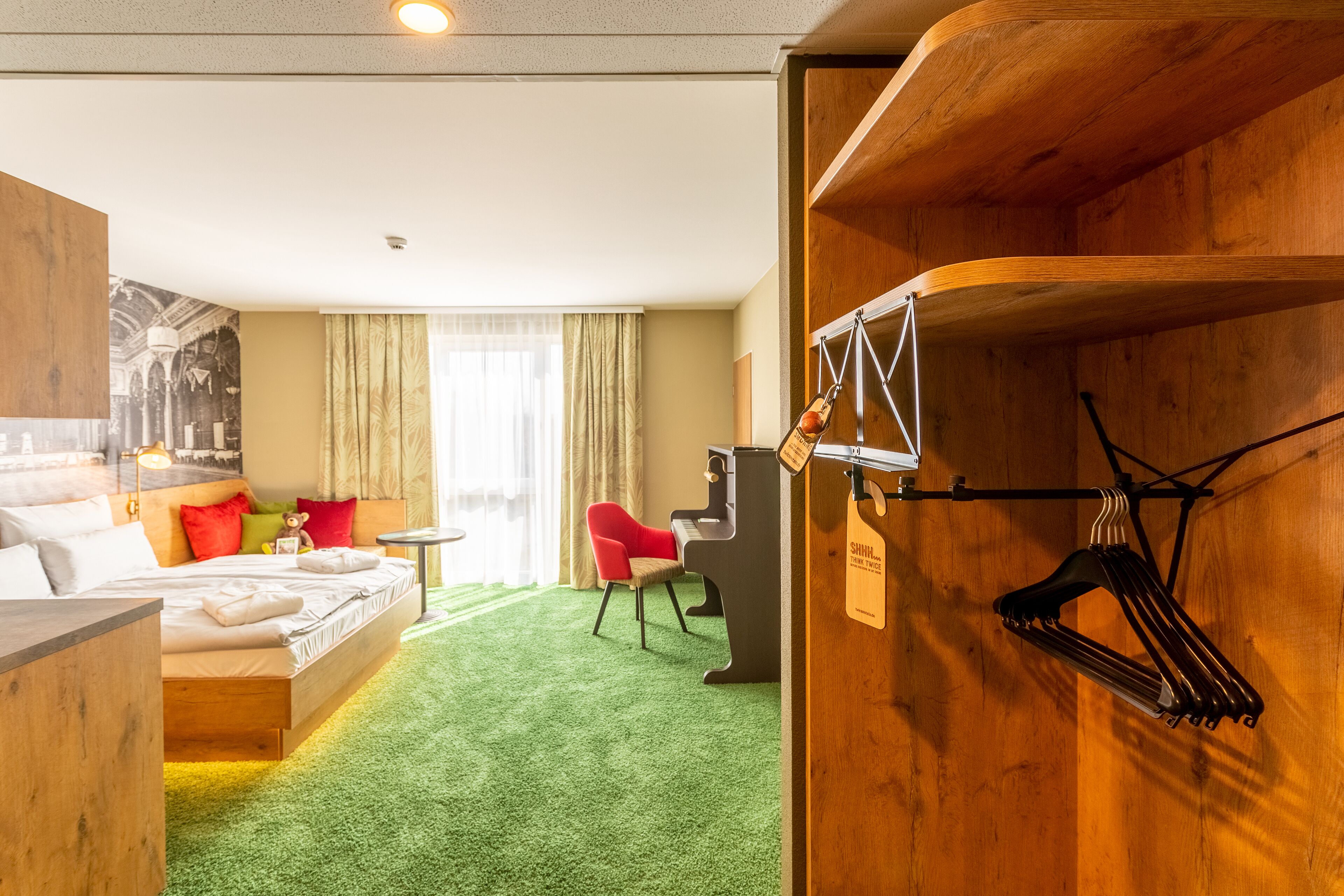 Una habitación de hotel con una cama, un escritorio, una silla y un piano.