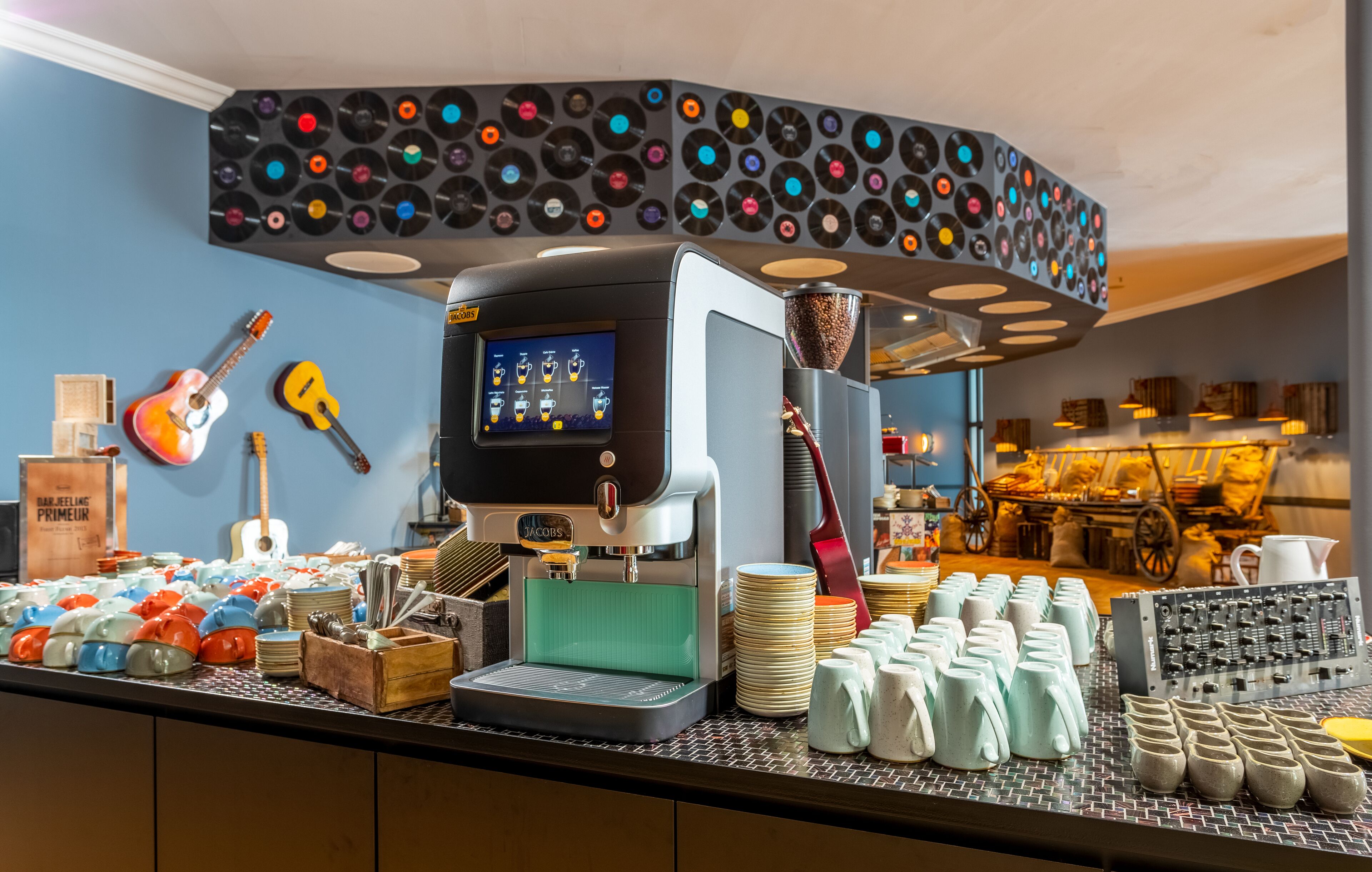 Un café proposant un expresso préparé avec une machine moderne, une variété de tasses et un mur décoré de disques vinyles.