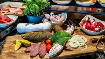 Una selección de embutidos curados, encurtidos y verduras frescas sobre una tabla de madera.