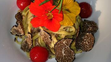 Un plato de comida con pasta, tomates rojos y trufas.
