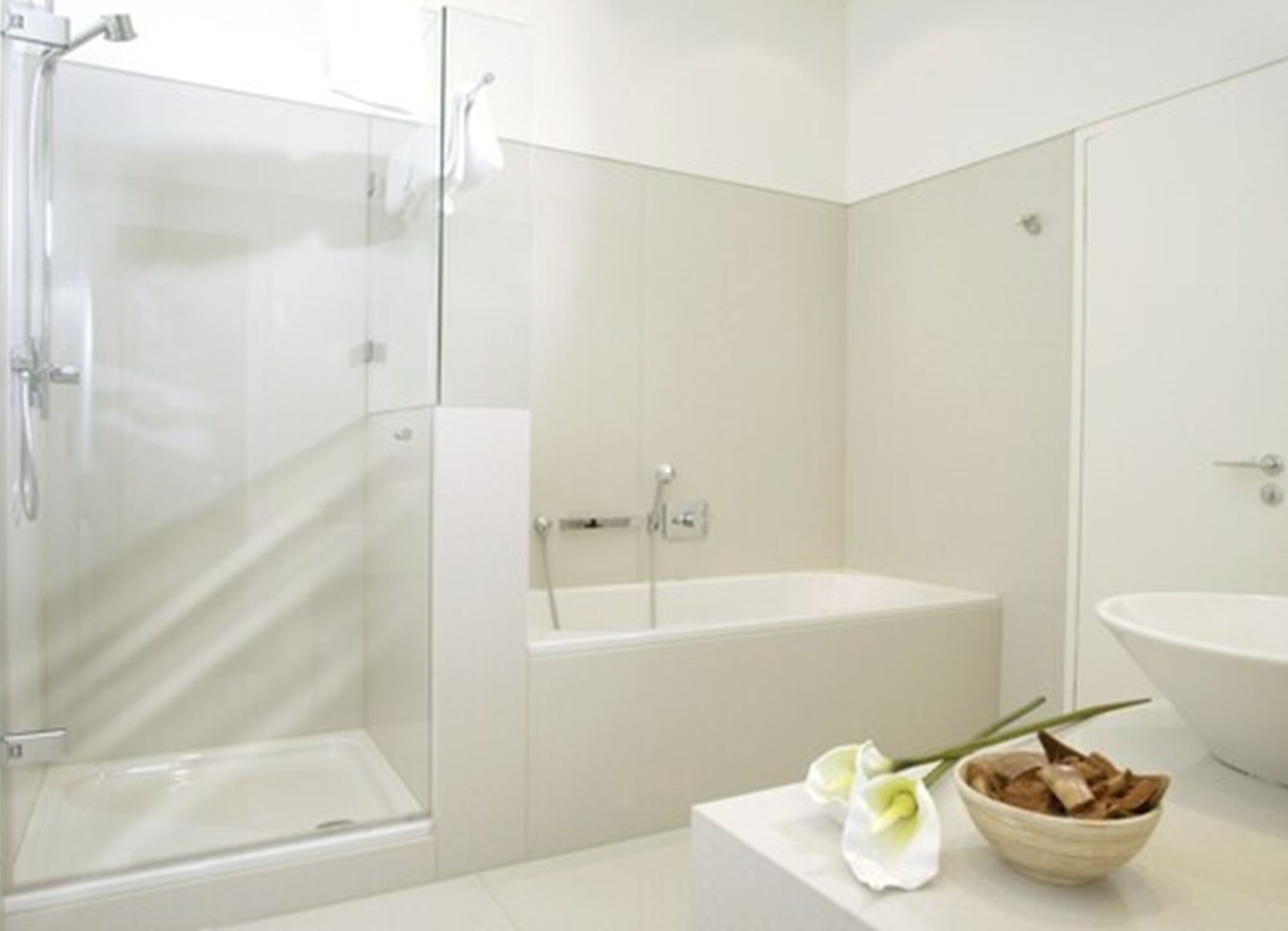 Un baño moderno con cabina de ducha de vidrio, una bañera independiente y un lavamanos grande.
