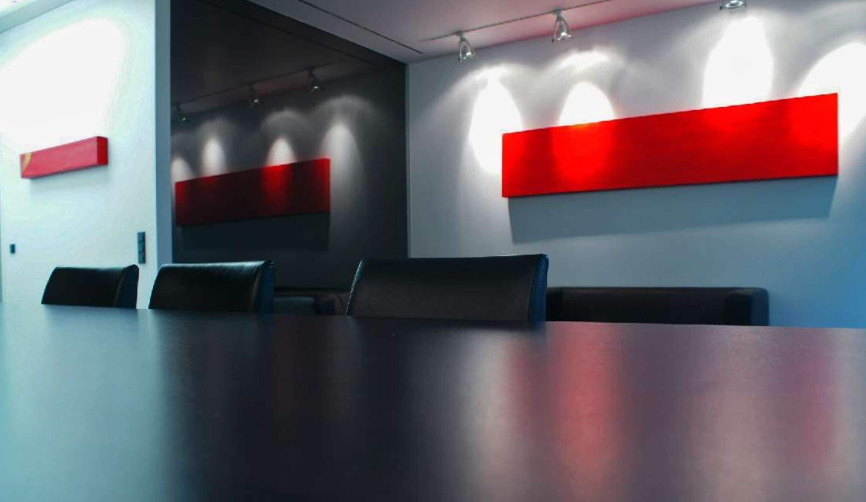 A conference room with a long table, several chairs, and red accent walls.