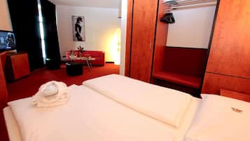 A hotel room with a bed, a red sofa, a small table, and a TV.