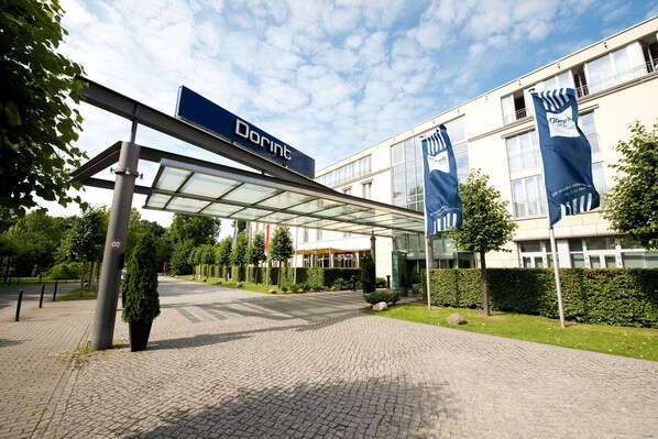 A Dorint hotel entrance with a covered walkway, glass facade, and banners. - Dorint Hotel Potsdam (Potsdam)
