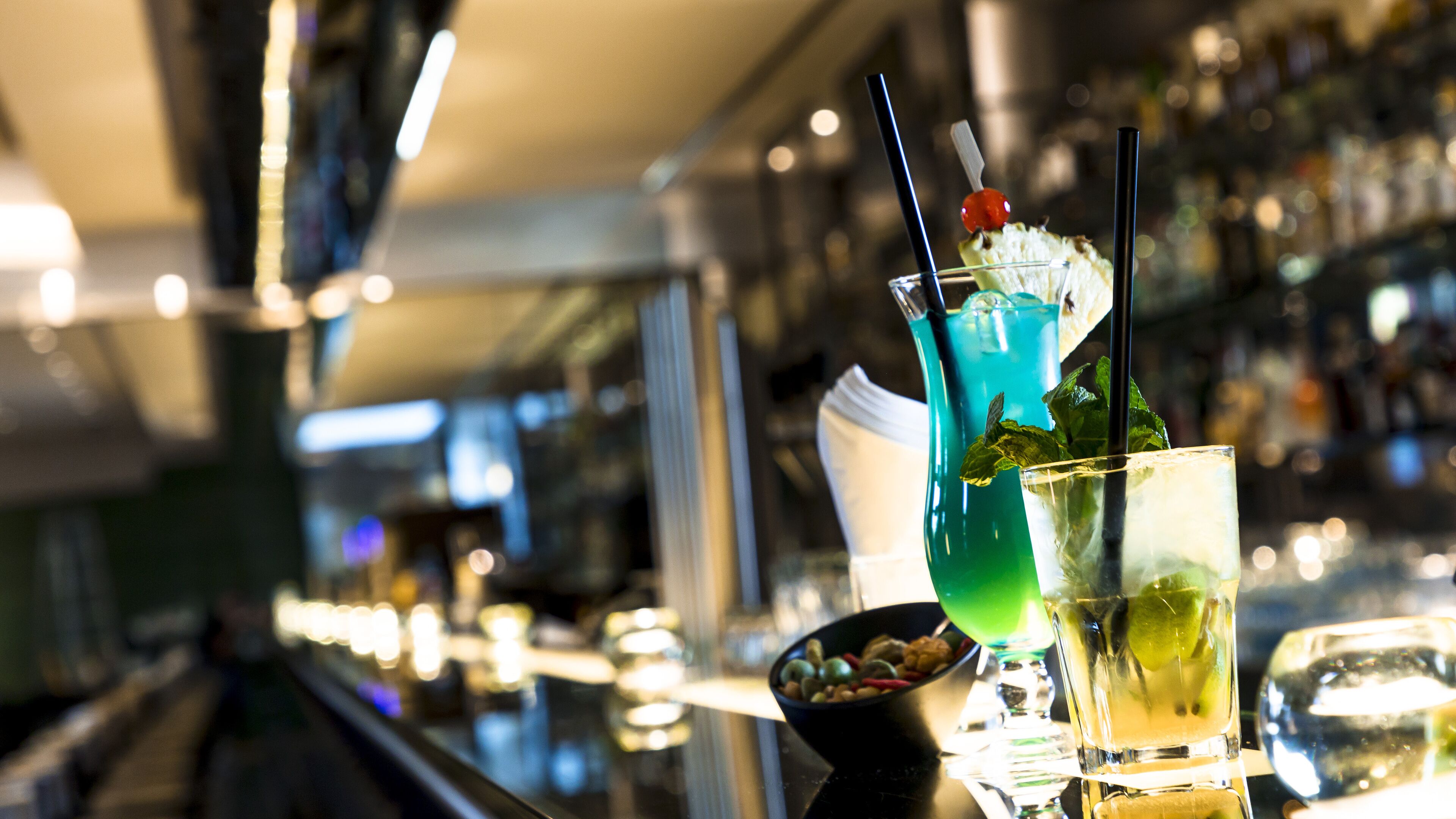 A bar area with various drinks and a bowl of nuts.