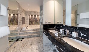 A modern bathroom with a large bathtub, two sinks, marble flooring, and a glass shower enclosure. - Dorint Hotel Potsdam (Potsdam)