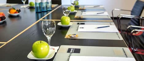 A conference table with nameplates, water bottles, glasses, and apples.