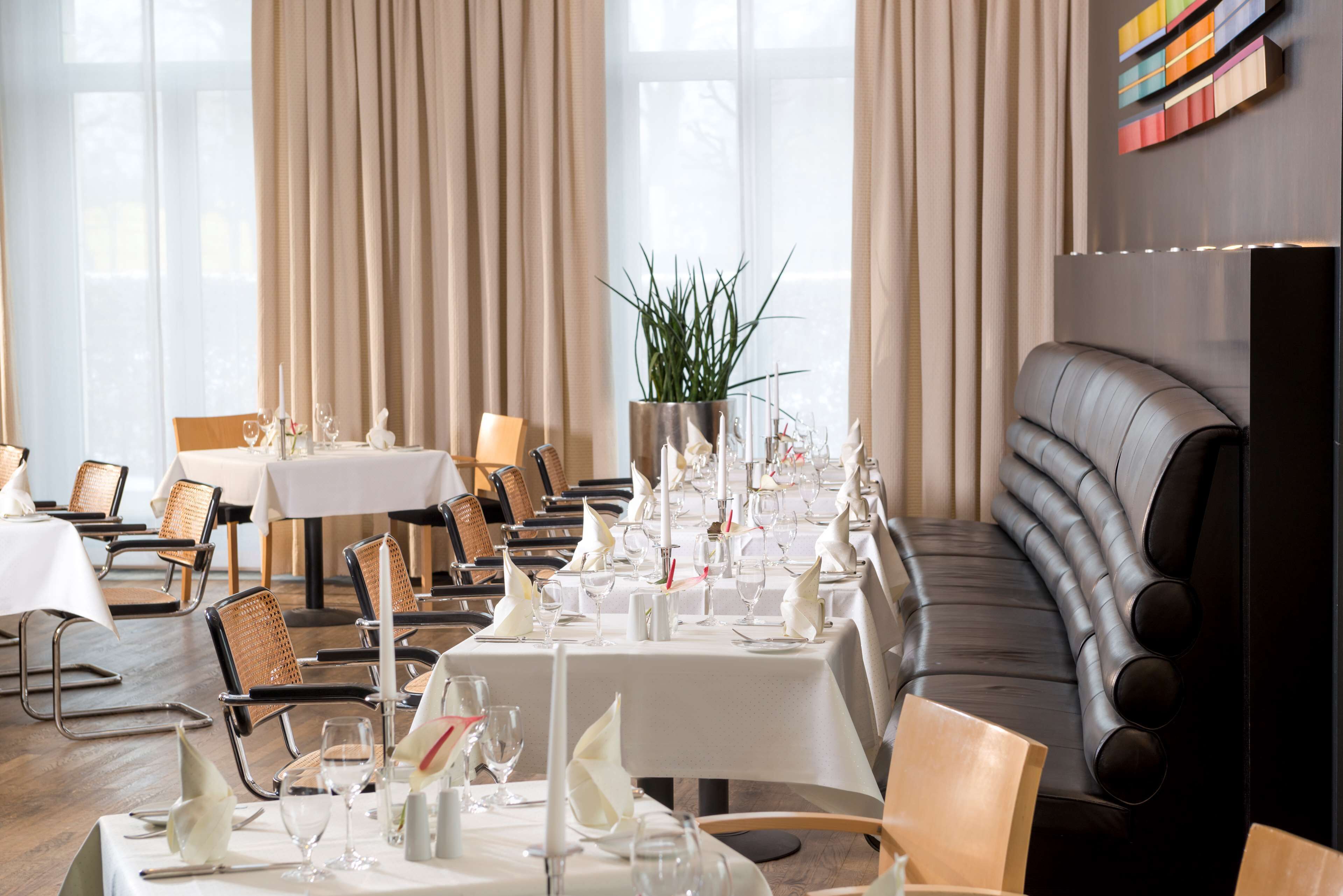 A dining area with tables set for a meal, chairs, and a sofa.