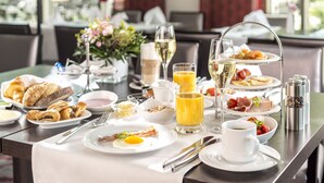 A breakfast setting with plates of food, a glass of orange juice, a glass of white wine, and a cup of coffee. - Dorint Hotel Potsdam (Potsdam)