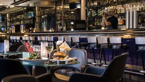 A bar area with a table set for two, featuring a meal, a glass of wine, and a beer tap. - Dorint Hotel Potsdam (Potsdam)