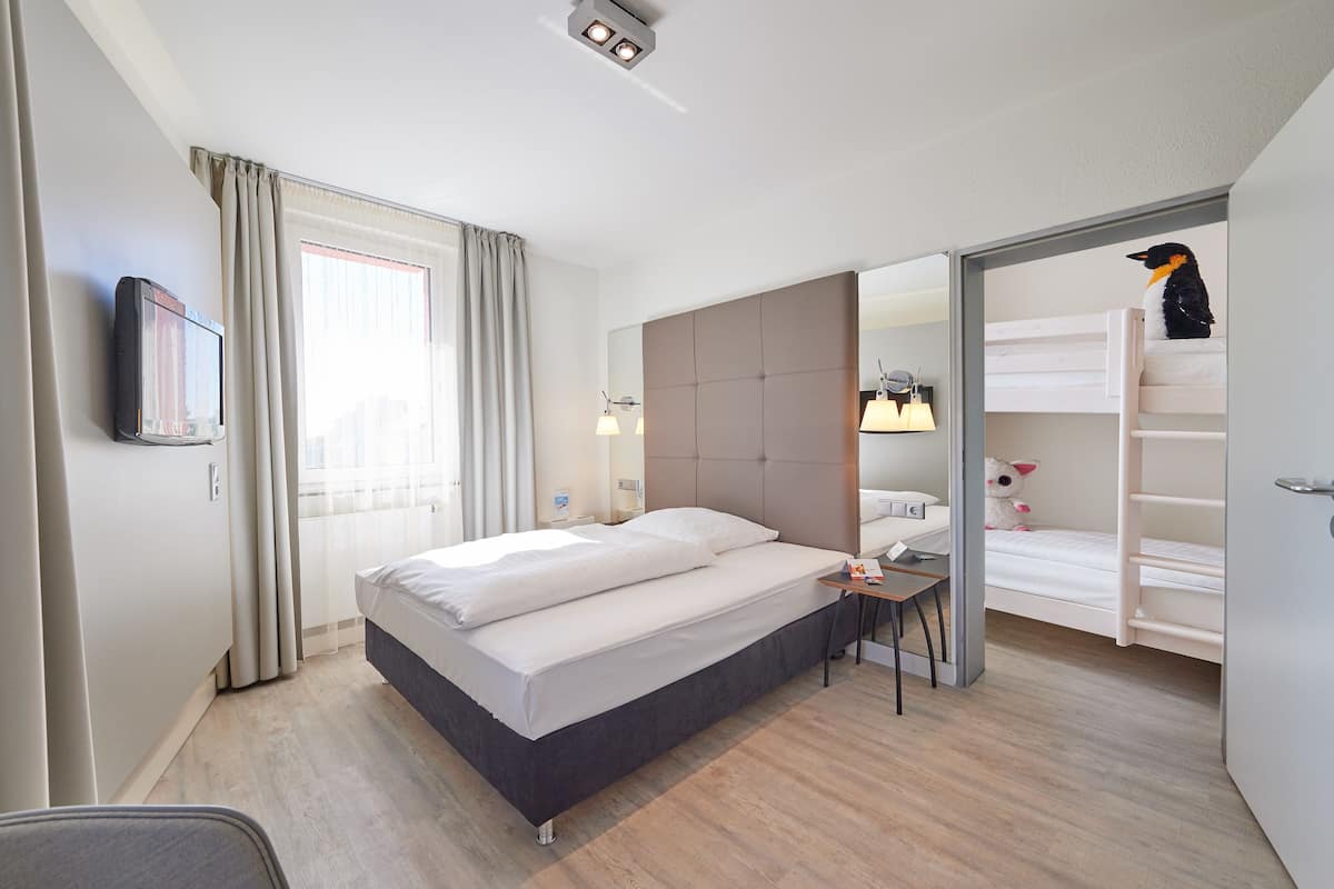 A hotel room with a bed, bedside table, lamp, and a mirror.