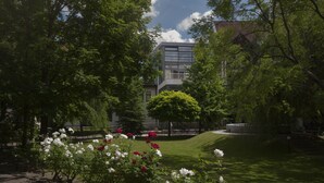 Un patio con un edificio moderno, un césped bien cuidado y arbustos florecientes.