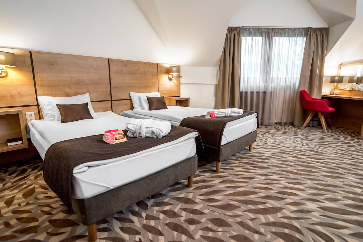 A hotel room with two beds, a desk, and a chair.