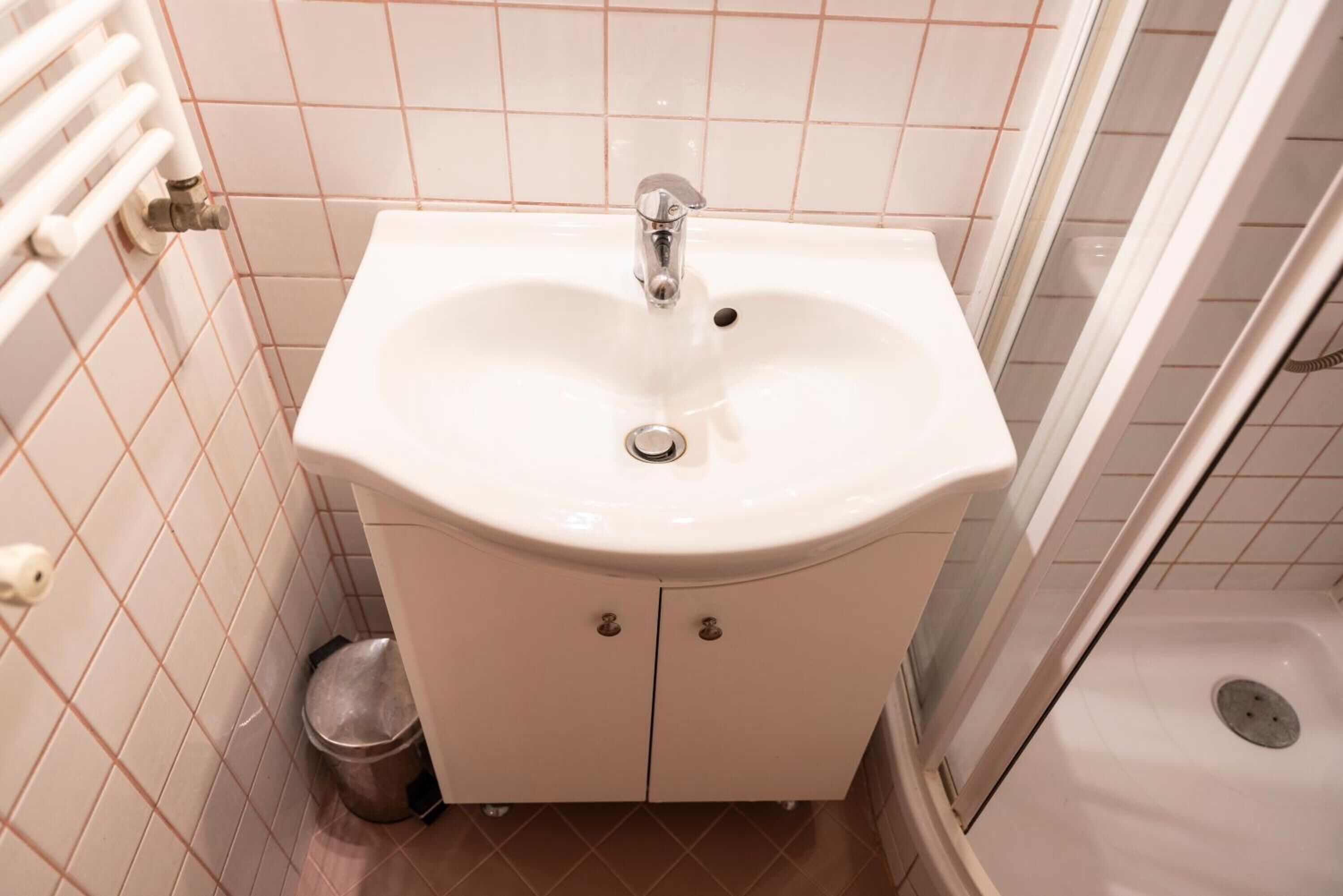 Ein Badezimmer mit einem weißen Waschbecken, einem Spiegel und einer Dusche.