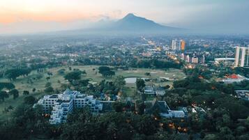 A hotel complex with multiple buildings, surrounded by greenery and a view of a distant mountain.