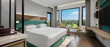 A modern hotel room with a large bed, a desk, and a view of the outdoors.