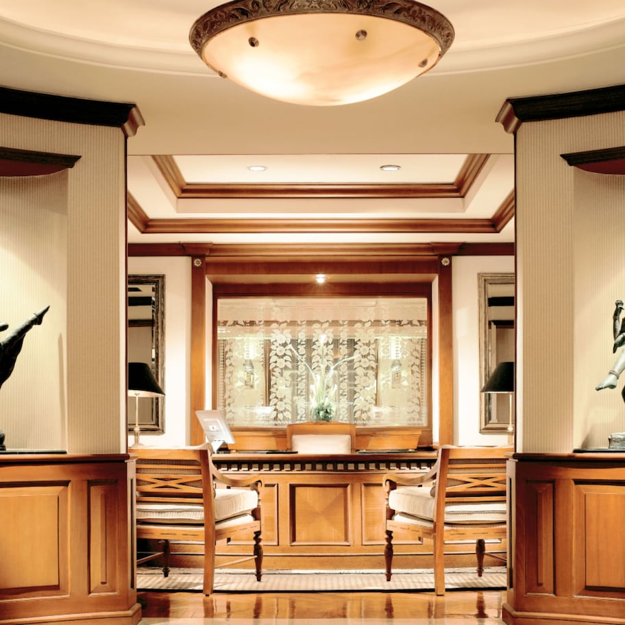 A lobby with wooden paneling, a piano, and two statues on either side.