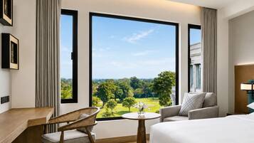 Ett hotellrum med ett stort fönster, en säng, ett skrivbord, en stol och ett litet bord.