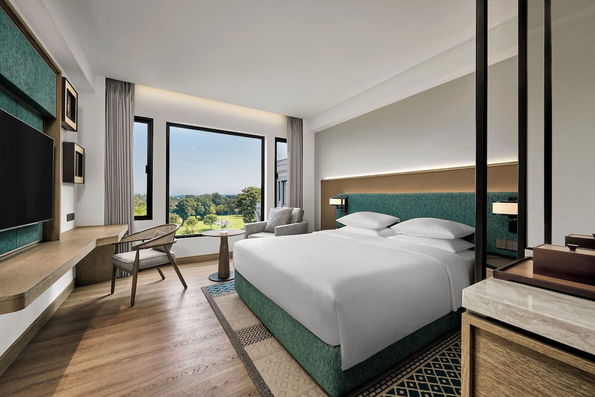 A modern hotel room with a large bed, a desk, a chair, and a TV.