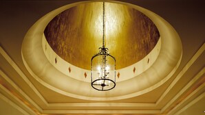 A grand lobby with a large circular marble floor, a central reception desk, and a high ceiling with a chandelier.