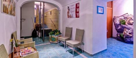 A reception area with wicker chairs, a magazine on a table, a poster on the wall, and a tiled floor.