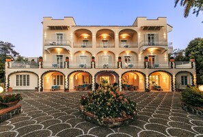 Stucco walls and terracotta roof tiles adorn this Mediterranean-inspired hotel, featuring a central courtyard with a circular flower arrangement.