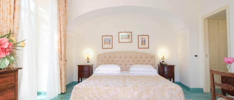 Une chambre à coucher bien rangée, avec un grand lit, deux tables de chevet et un luminaire fixé au mur.