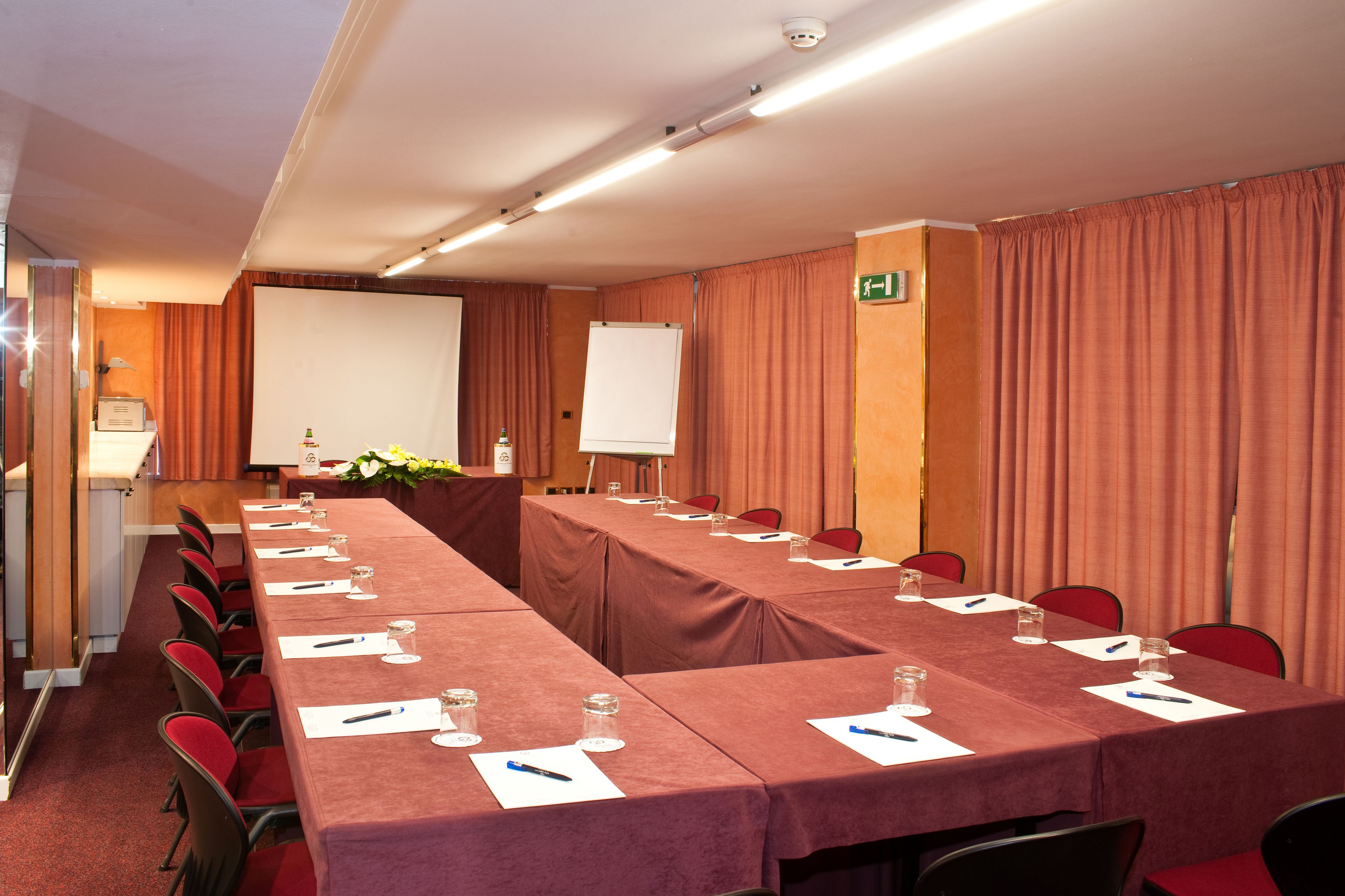 A conference room with a long table, red chairs, and a whiteboard.
