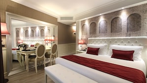 Ein Hotelzimmer mit einem großen Bett, einem Nachttisch, einem Sessel, einem Schreibtisch und einem Spiegel.