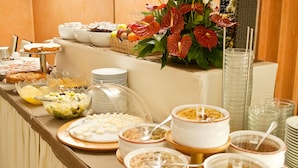 Ein Buffet mit verschiedenen Speisen und Getränken, darunter Obst, Getreideprodukten und Desserts.