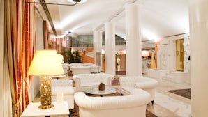 Eine geräumige Lobby mit weißen Sofas, einem runden Couchtisch und einer Lampe.