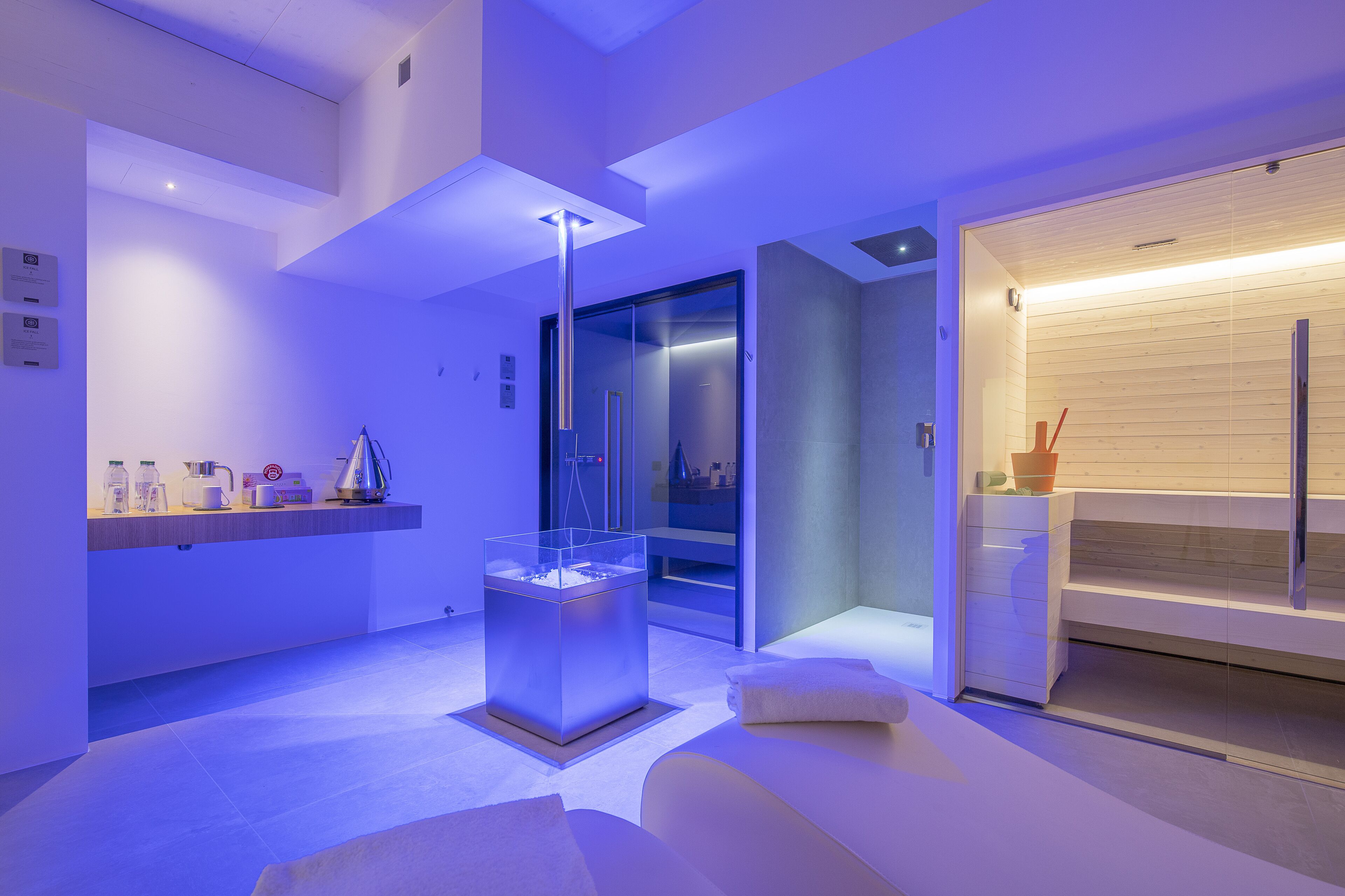 A modern hotel lobby with a reception desk, a glass elevator, and a seating area.