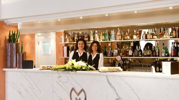 A bar area with a marble countertop, a variety of liquor bottles, and a floral arrangement.