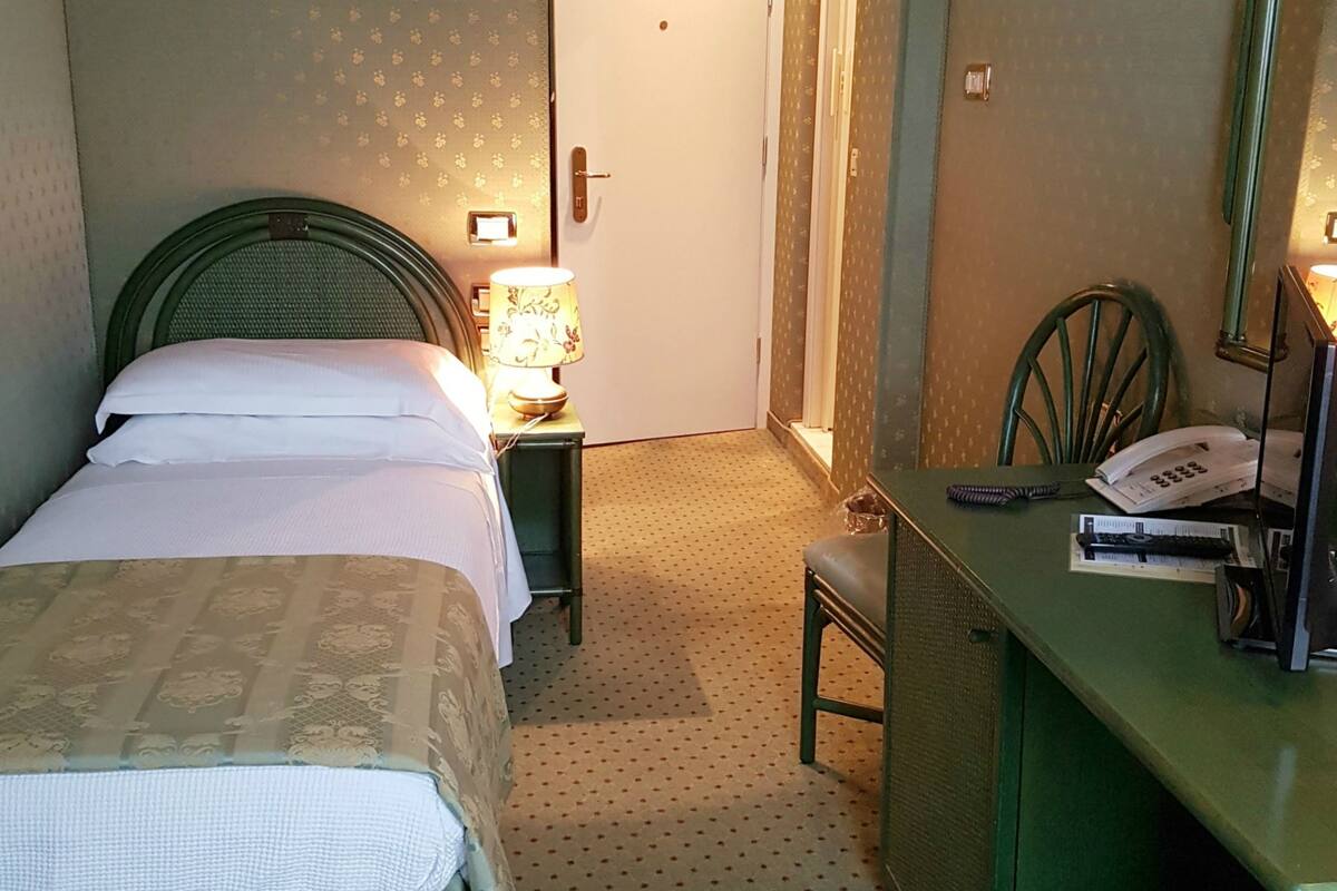 A hotel room with two beds, a desk with a telephone, and a chair.