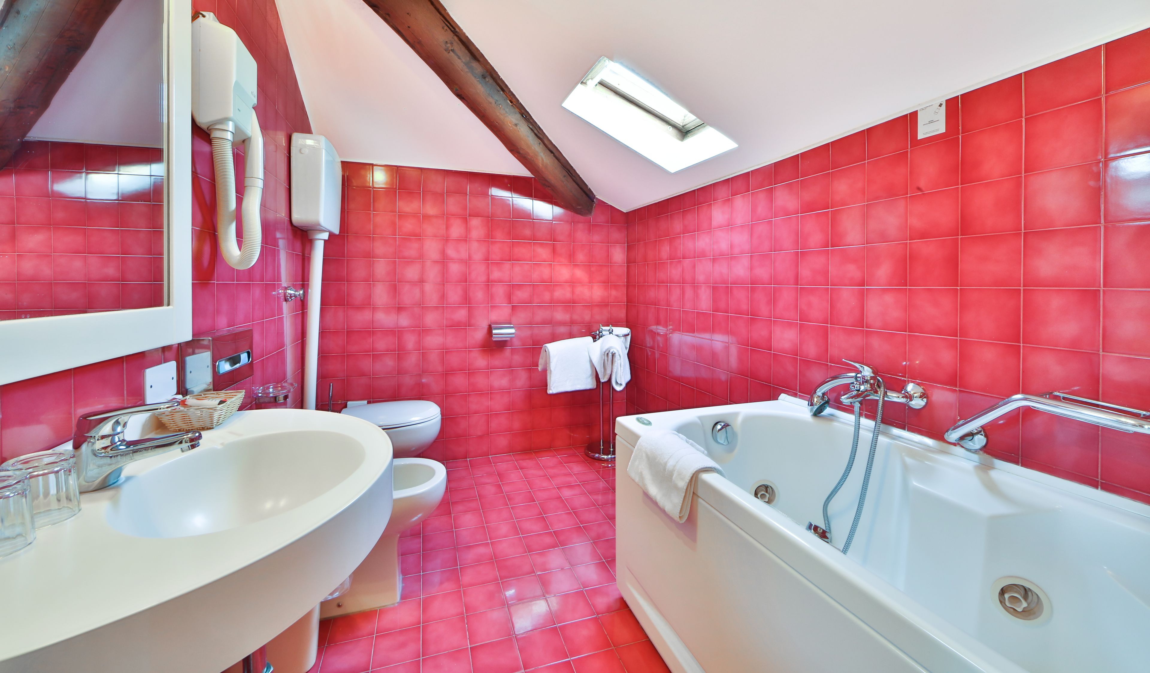 A bathroom with red tiles, a white sink, a toilet, and a bathtub.