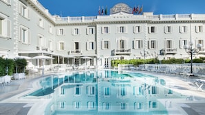 Una piscina grande rodeada de edificios blancos con balcones y banderas.